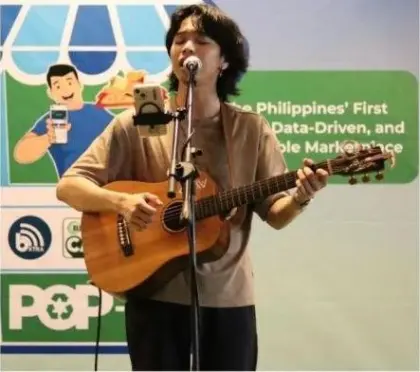 A musician playing acoustic guitar and singing on a small stage at the pop-up.
